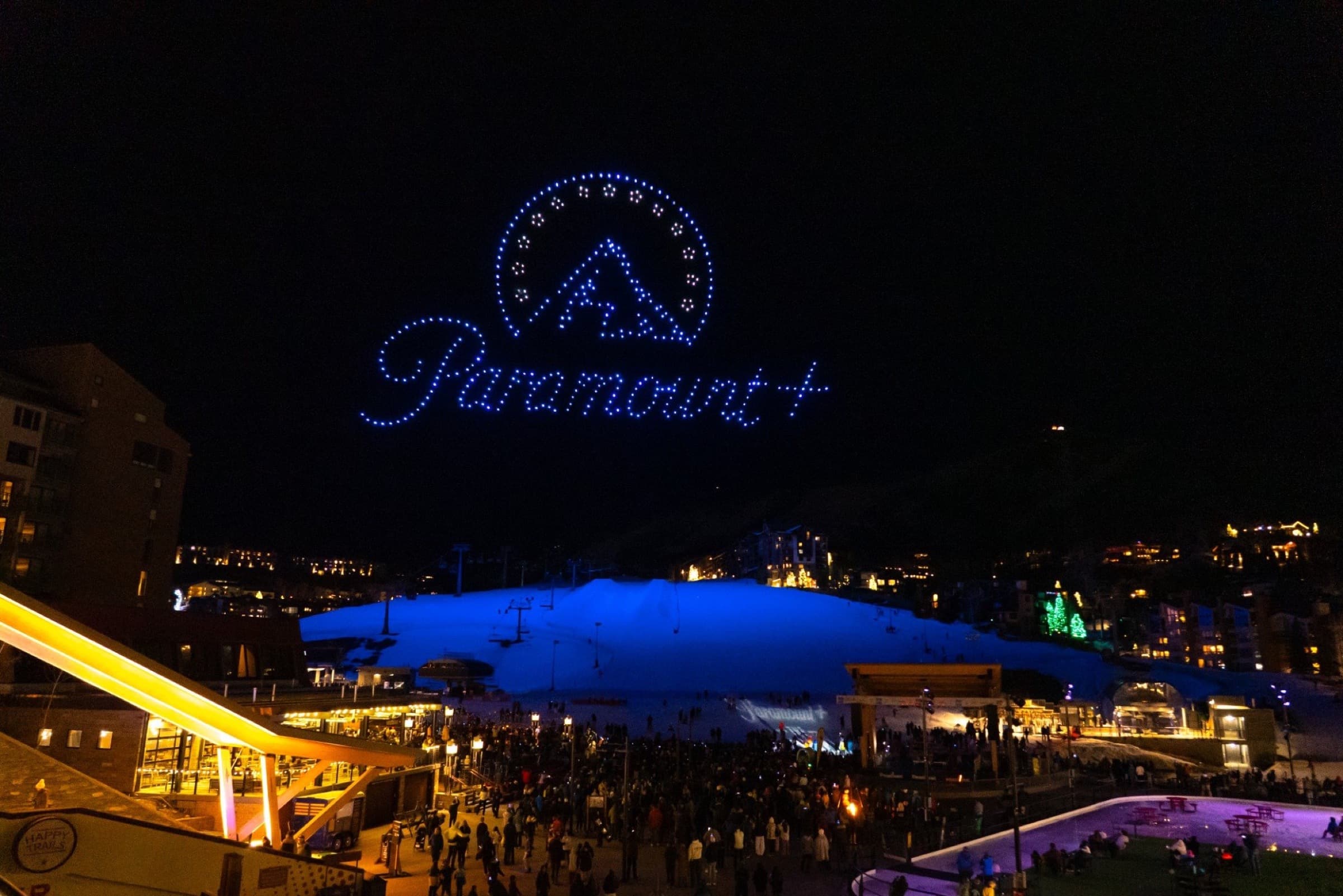 The Paramount+ logo drawn in drones above a lit ski slope