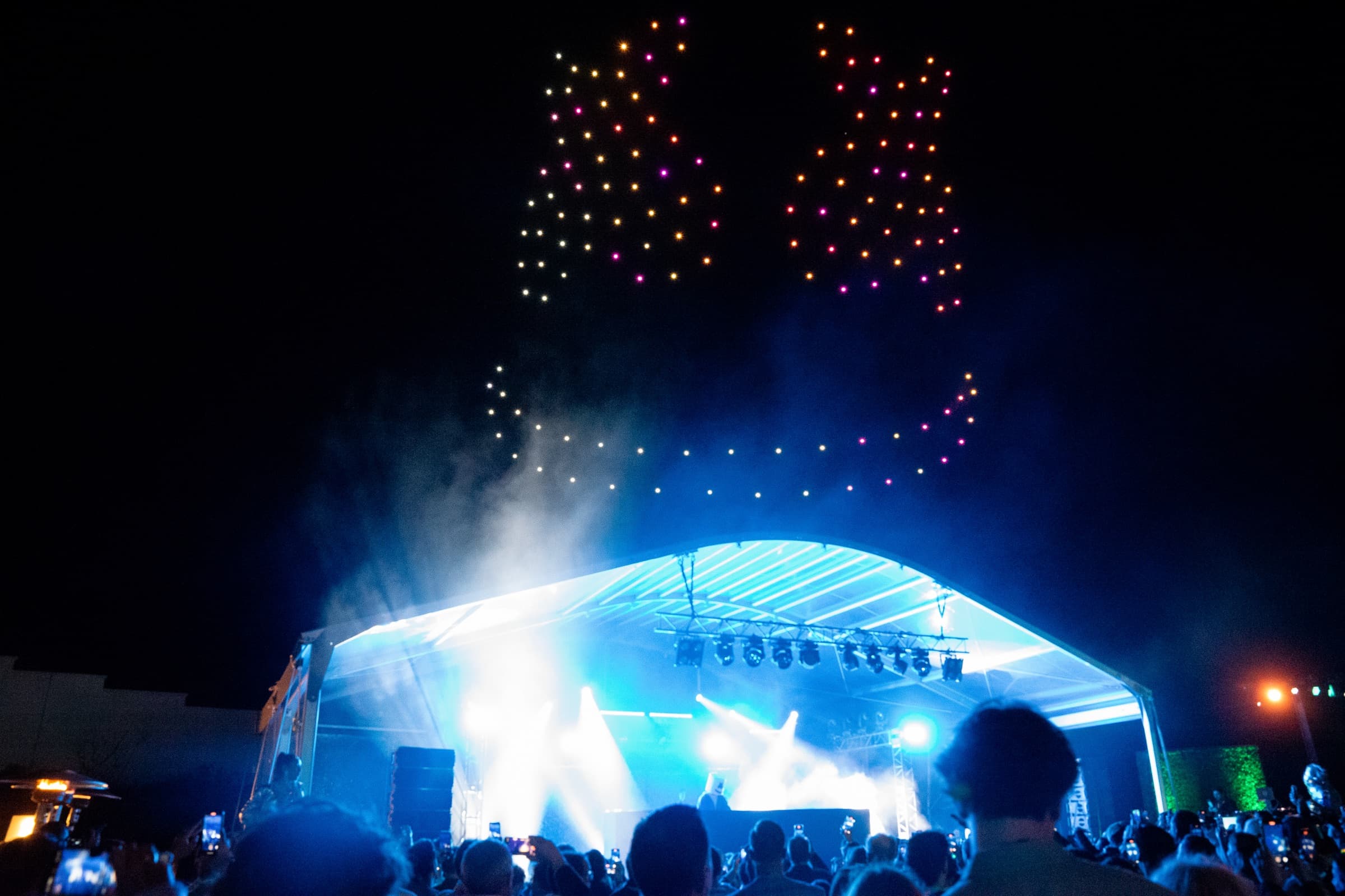 Marshmello logo drawn in drones above a lit stage